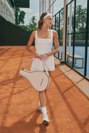 Model wearing the Rest & Repeat Court Pleated Mesh Dress in White, carrying the Rest & Repeat Court Padel Bag in Cream